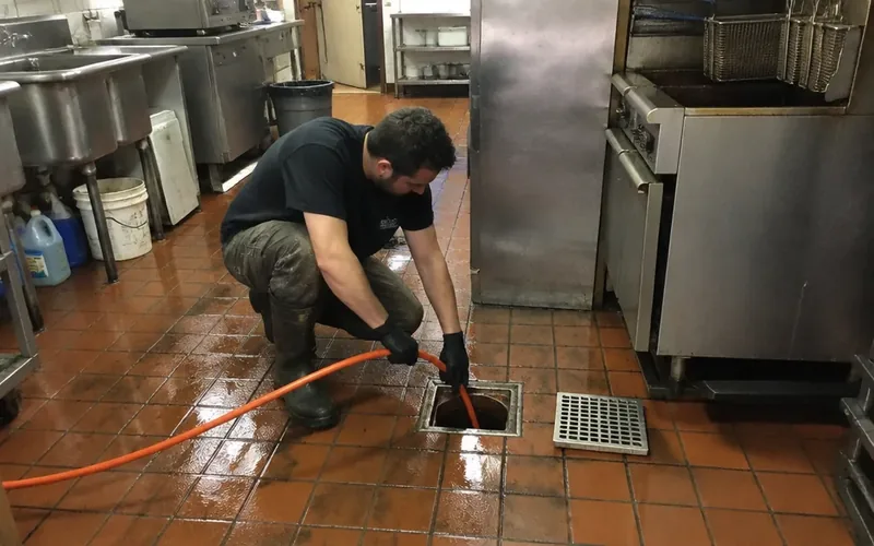 Technician jetting a grease-loaded floor drain in a Philadelphia restaurant kitchen